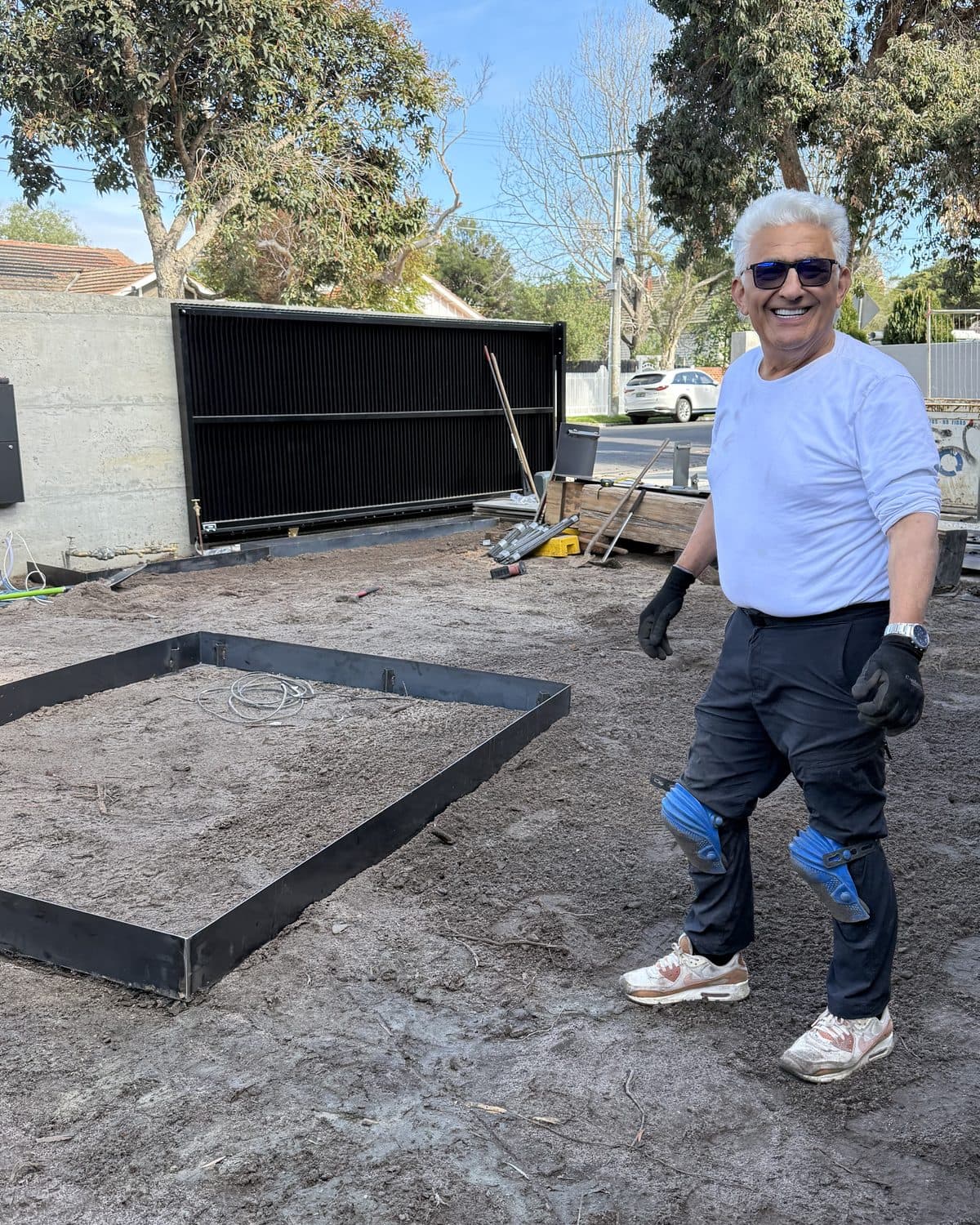 Mario smiling on site in the front garden of a new home build, beside a new steel-edged garden bed